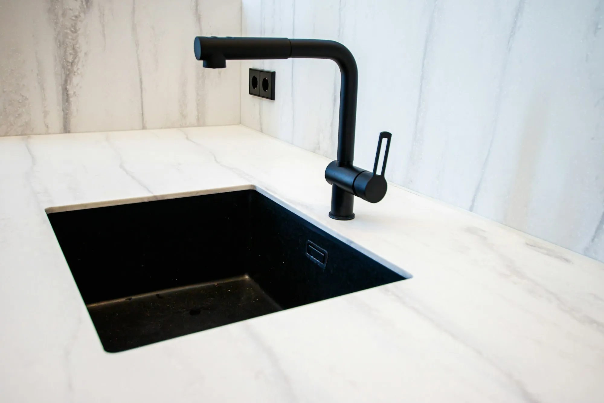 Water Filtration Services in Lake Forest, CA Black kitchen faucet over an undermount sink in a white stone counter