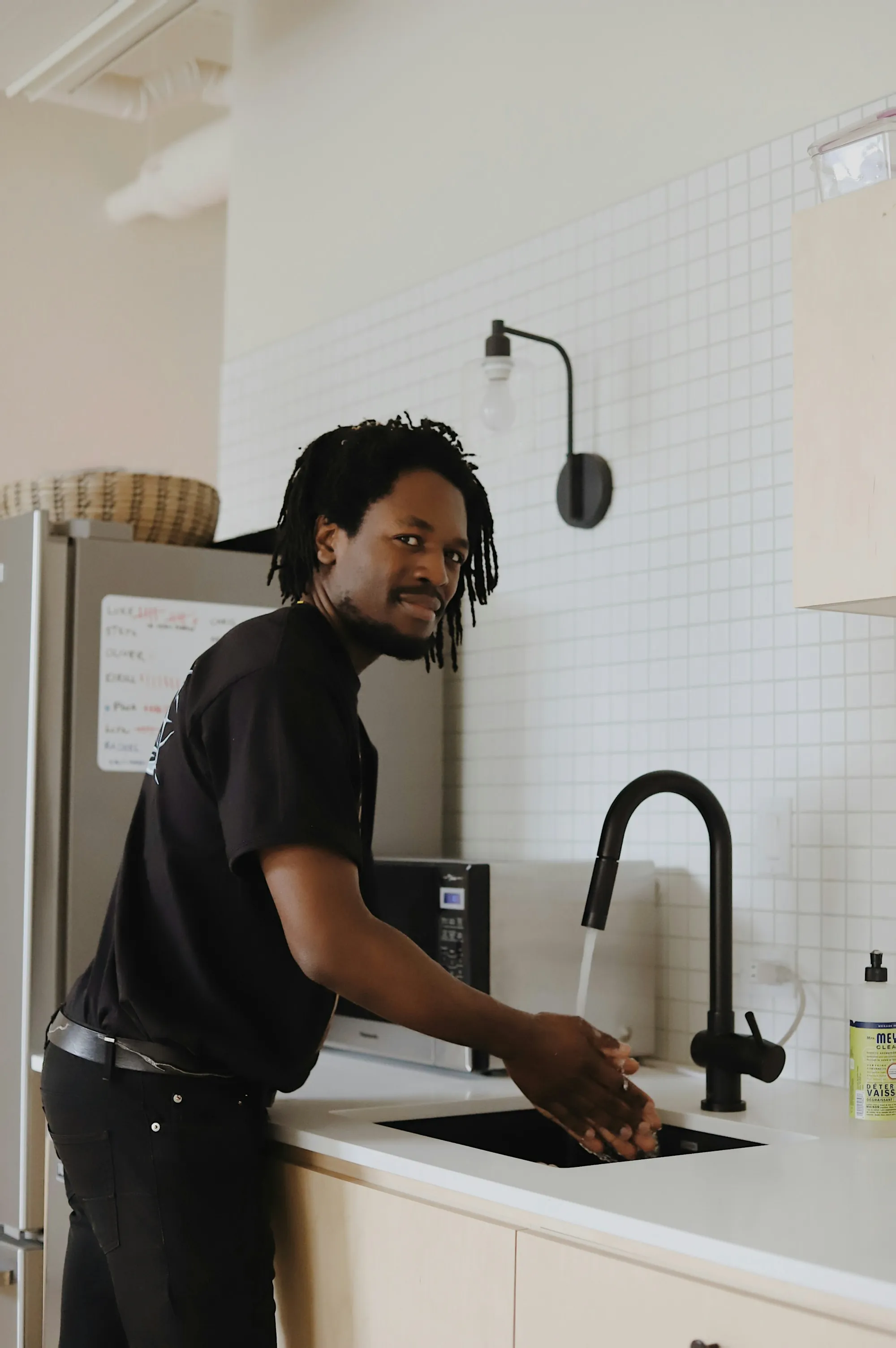 One Local Team for Every Water Problem Smiling man washing his hands at a kitchen sink with a black faucet