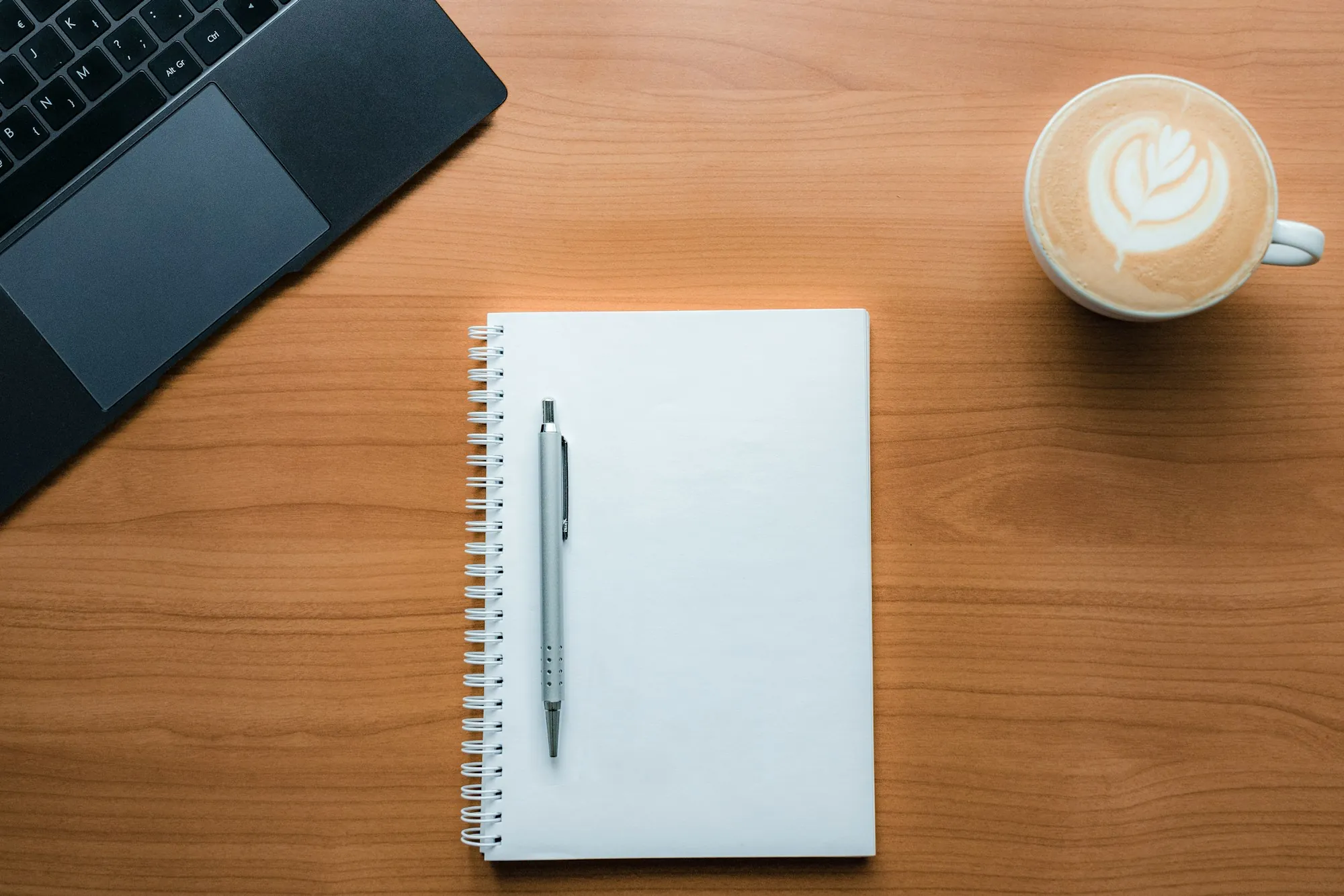 The Lake Forest Water Pros Blog Notebook, pen and a cup of coffee on a wooden table