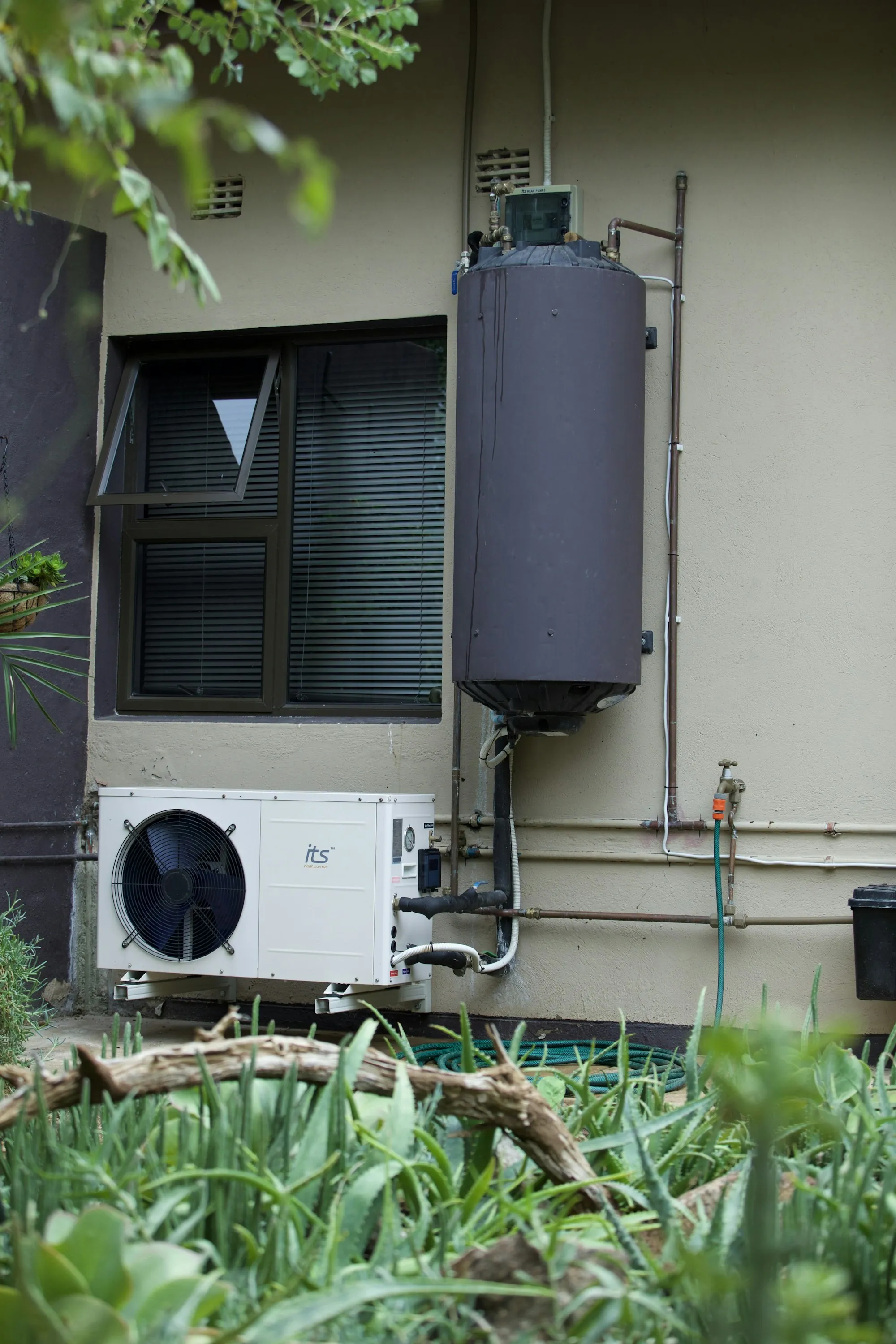 Scale Prevention & Water Heater Protection in Lake Forest, CA Residential water heater tank and heat pump unit on an exterior wall