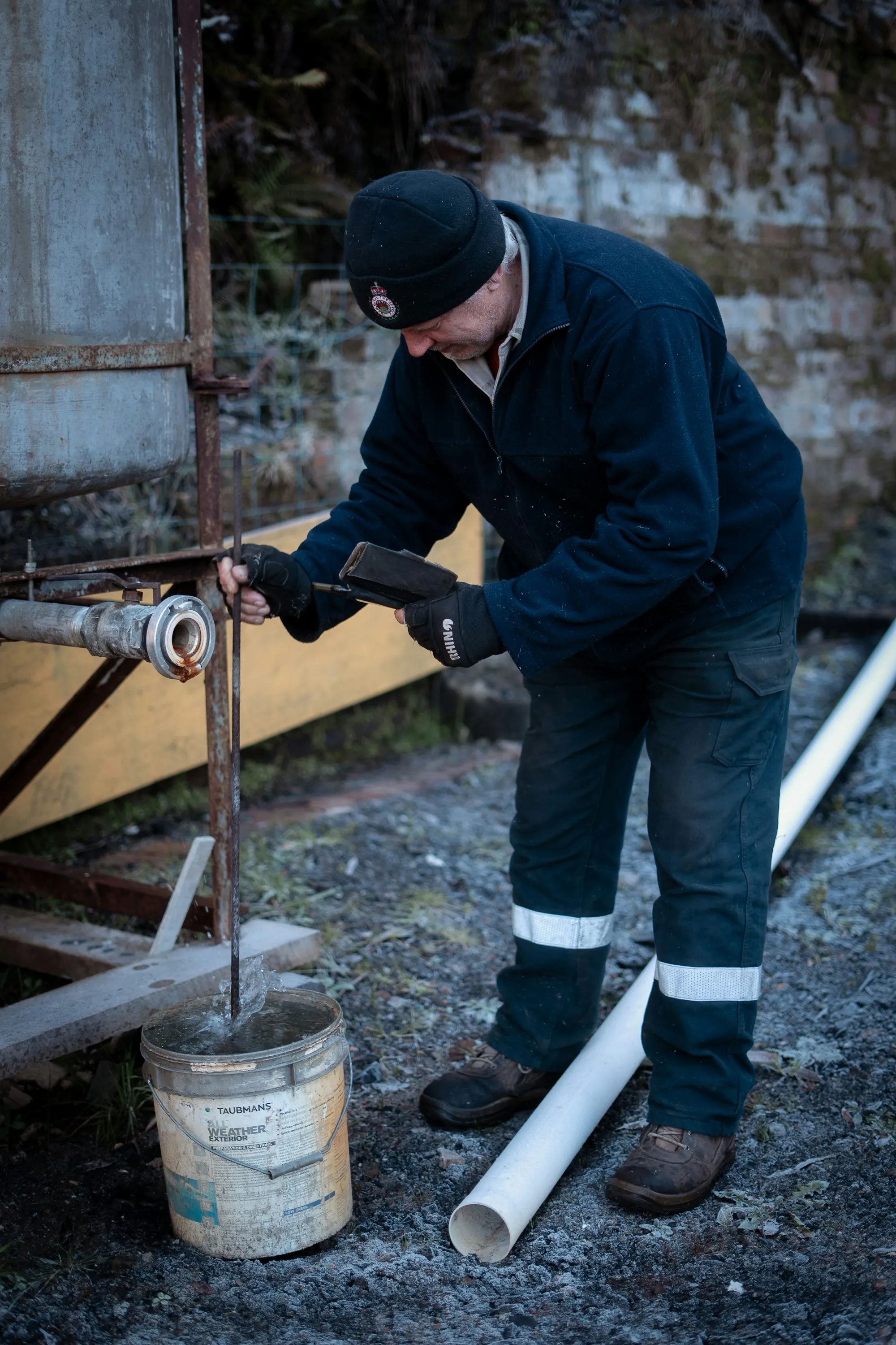 Local Water Experts Serving Lake Forest Worker in dark overalls fitting a pipe outdoors next to a bucket